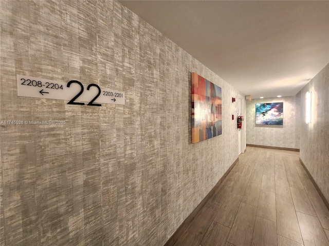 hallway with wallpapered walls and wood finished floors