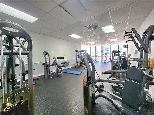 gym with baseboards and a paneled ceiling