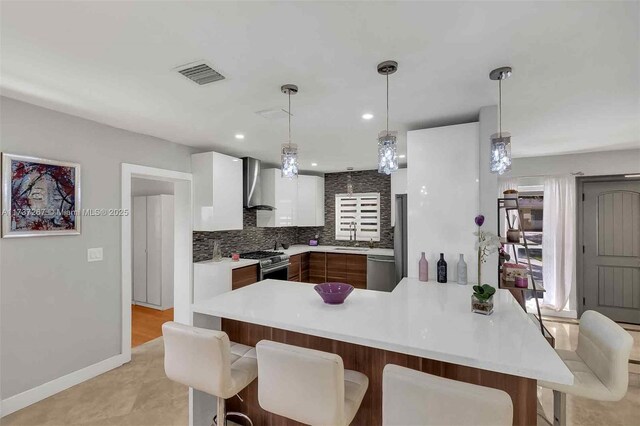 461 NE 115th St, Miami, FL 33161 - kitchen with wall chimney range hood, appliances with stainless steel finishes, a breakfast bar, light countertops, and white cabinets