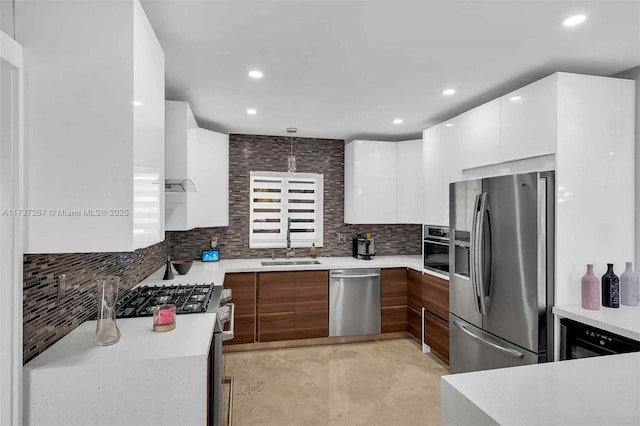 kitchen with decorative light fixtures, white cabinetry, sink, backsplash, and stainless steel appliances