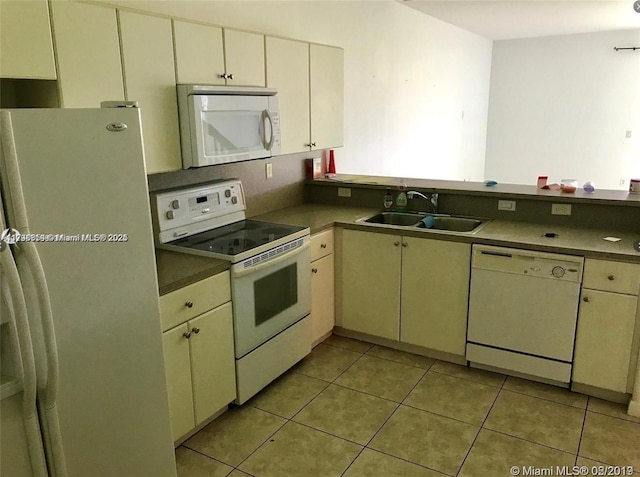 kitchen featuring light tile patterned flooring, sink, white appliances, and cream cabinetry