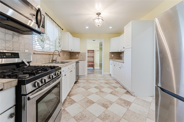 kitchen with appliances with stainless steel finishes, tasteful backsplash, light stone countertops, white cabinets, and sink