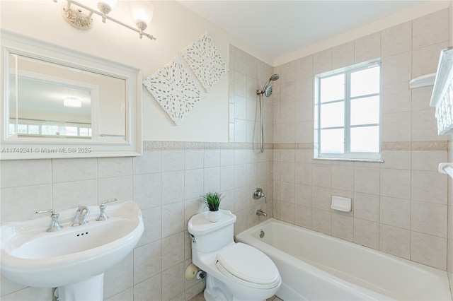 full bathroom featuring sink, toilet, tile walls, and tiled shower / bath combo