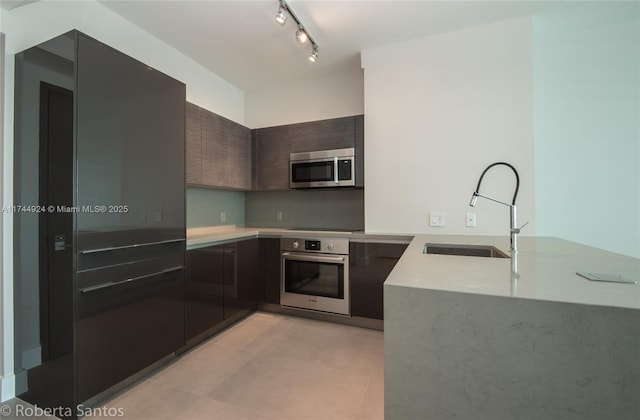 kitchen featuring dark brown cabinetry, sink, track lighting, kitchen peninsula, and stainless steel appliances