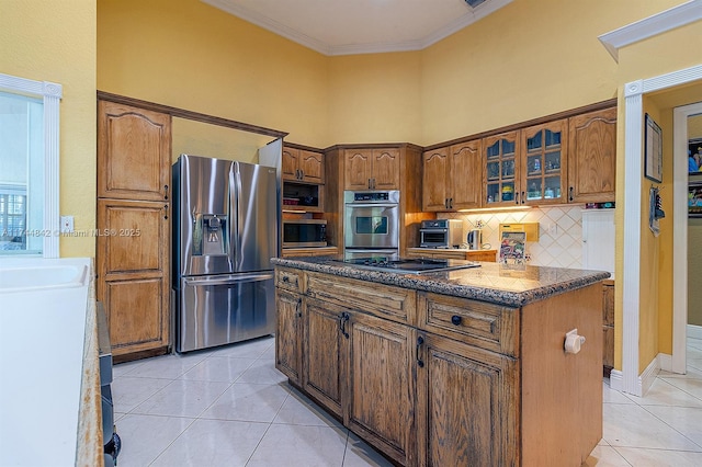 kitchen featuring tasteful backsplash, glass insert cabinets, ornamental molding, light tile patterned floors, and appliances with stainless steel finishes