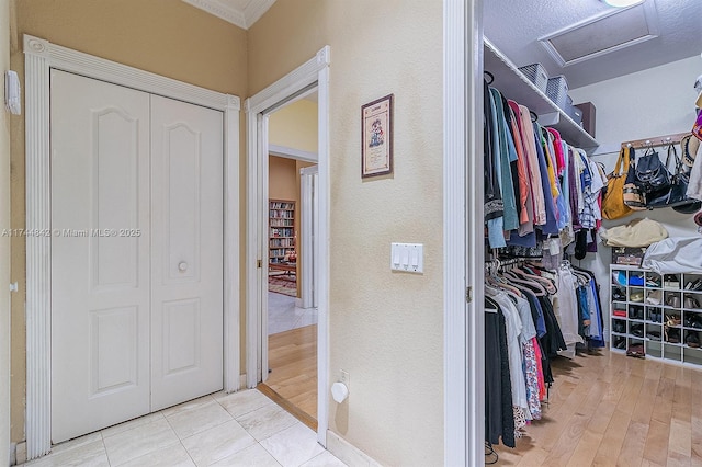 walk in closet with attic access and wood finished floors