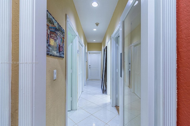 hall with light tile patterned floors, a textured wall, and recessed lighting