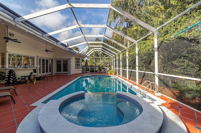 view of pool featuring a pool with connected hot tub, ceiling fan, french doors, a lanai, and a patio area