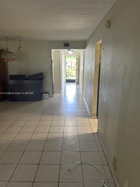 hallway featuring light tile patterned flooring and a textured ceiling