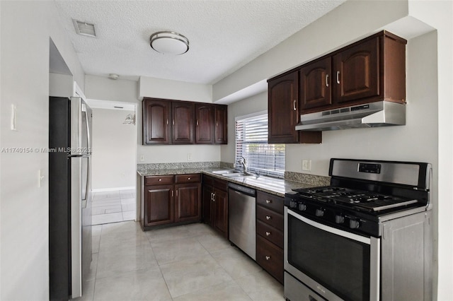 kitchen featuring stainless steel appliances, sink, dark brown cabinets, and a textured ceiling