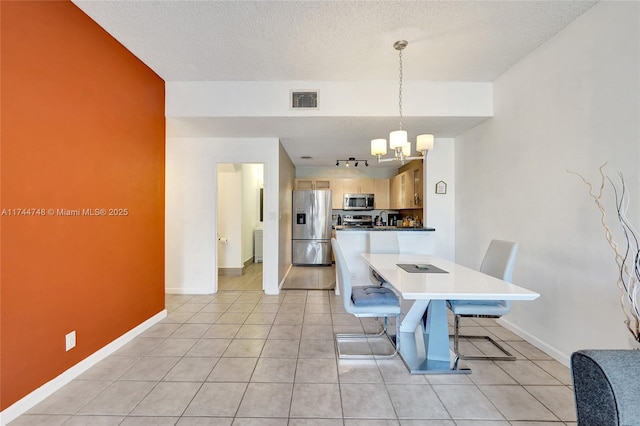 tiled dining area with radiator heating unit, track lighting, a notable chandelier, and a textured ceiling