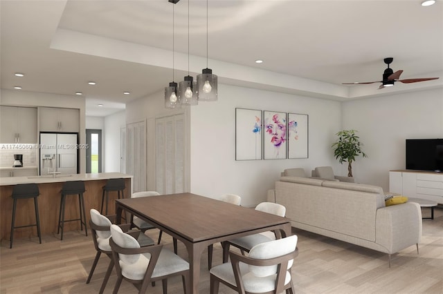 dining room with ceiling fan, a raised ceiling, and light wood-type flooring