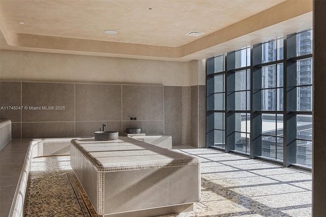 bathroom featuring a towering ceiling and tile walls