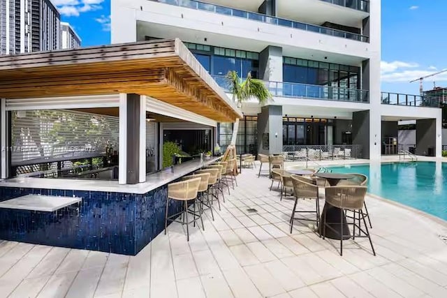 rear view of property with a community pool and an outdoor bar