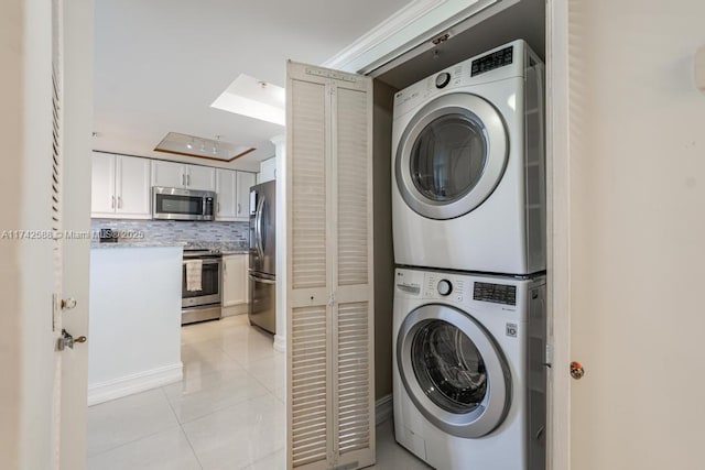 laundry room featuring light tile patterned flooring, stacked washing maching and dryer, and laundry area