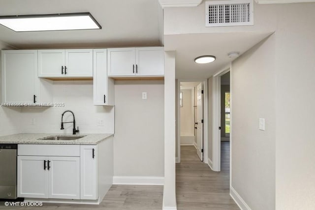 kitchen featuring white cabinetry, dishwasher, light stone countertops, and sink