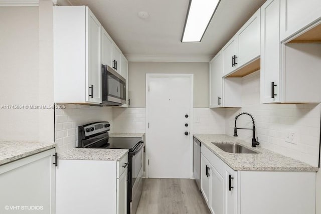 kitchen featuring sink, white cabinetry, light stone counters, light wood-type flooring, and appliances with stainless steel finishes