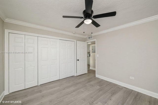 unfurnished bedroom with ornamental molding, a textured ceiling, light wood-type flooring, and a closet