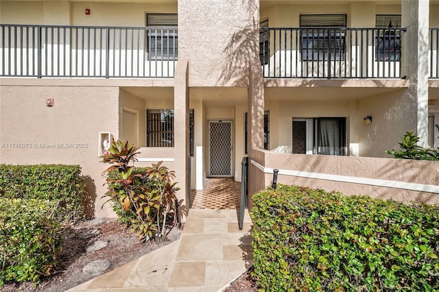 doorway to property featuring a balcony and stucco siding