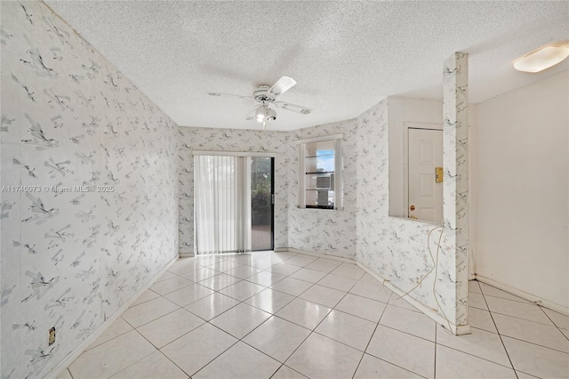 spare room with ceiling fan, a textured ceiling, light tile patterned flooring, baseboards, and wallpapered walls