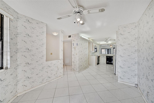 spare room featuring light tile patterned floors, a textured ceiling, a ceiling fan, and wallpapered walls