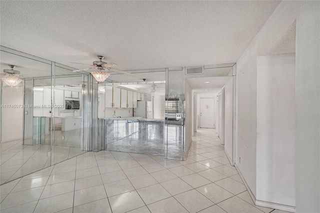 spare room featuring a ceiling fan, visible vents, a textured ceiling, and light tile patterned flooring