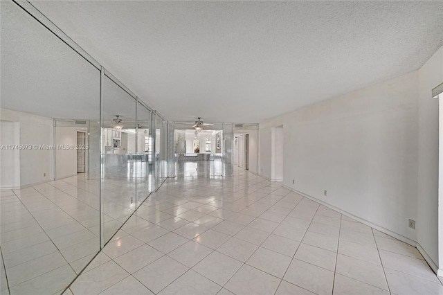 unfurnished room featuring a textured ceiling, light tile patterned flooring, and a ceiling fan