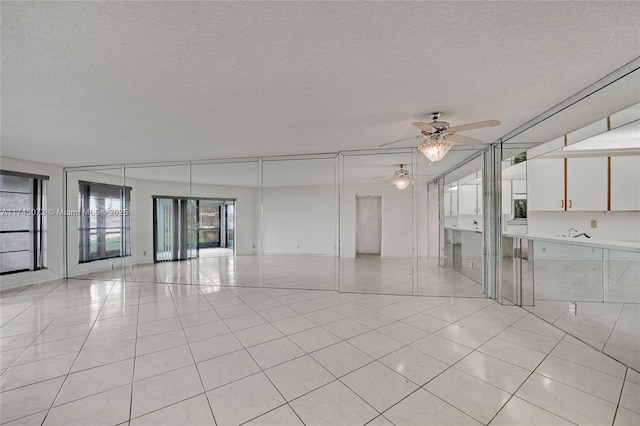 unfurnished living room with ceiling fan, a textured ceiling, and light tile patterned flooring