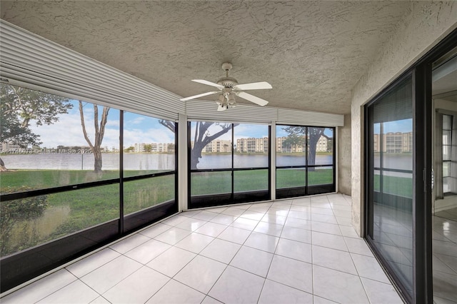 unfurnished sunroom featuring a healthy amount of sunlight, a water view, and ceiling fan