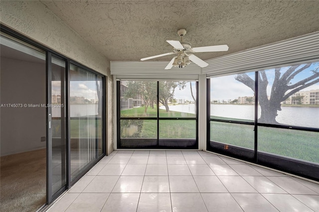 unfurnished sunroom featuring ceiling fan and a water view