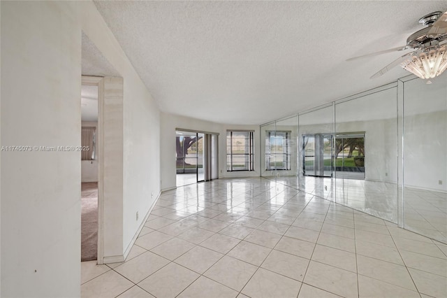 unfurnished room featuring ceiling fan, a textured ceiling, baseboards, and light tile patterned floors