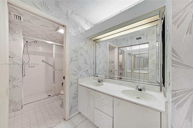 bathroom featuring a stall shower, a sink, and wallpapered walls