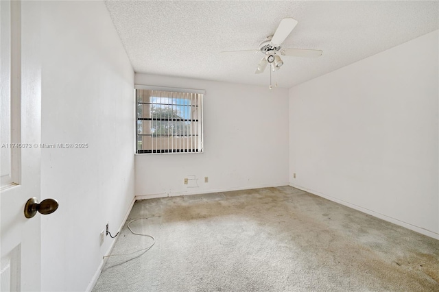 carpeted spare room featuring ceiling fan, baseboards, and a textured ceiling