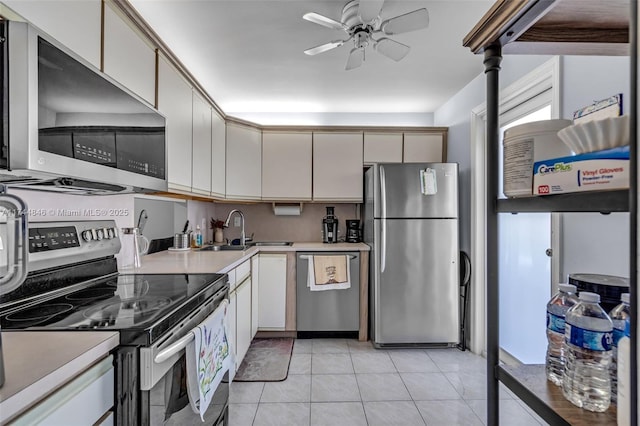 kitchen with light tile patterned flooring, appliances with stainless steel finishes, sink, and ceiling fan