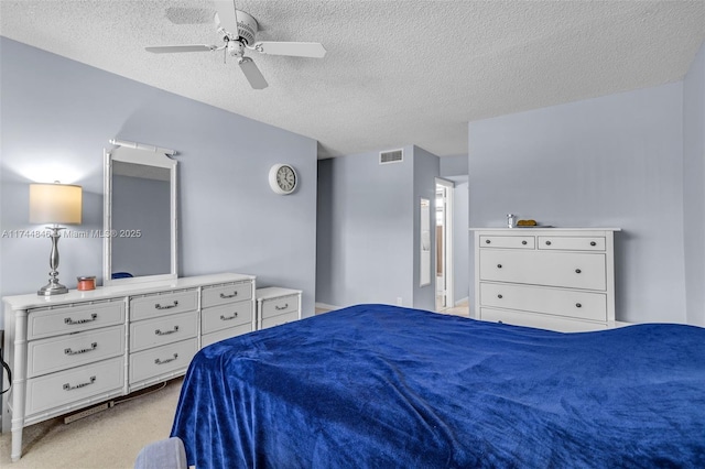 bedroom with ceiling fan, light colored carpet, and a textured ceiling