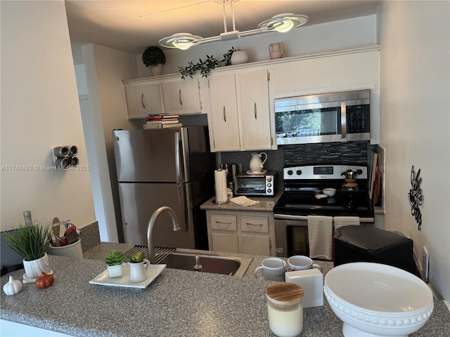 kitchen with tasteful backsplash, appliances with stainless steel finishes, sink, and white cabinets