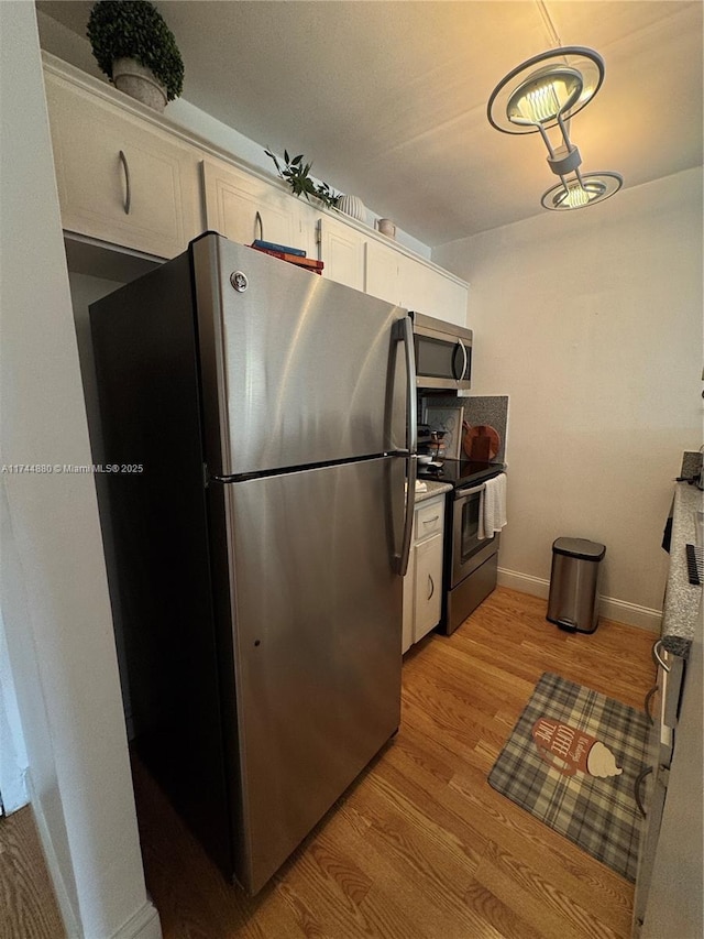 kitchen with light hardwood / wood-style floors, white cabinets, and appliances with stainless steel finishes