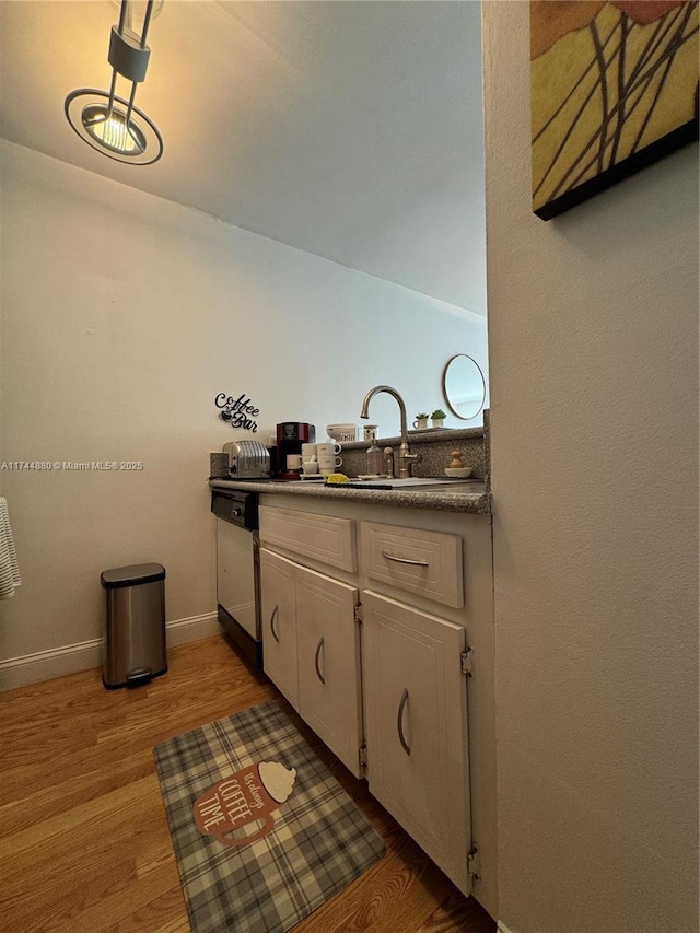 kitchen featuring white cabinetry, sink, light hardwood / wood-style flooring, and stainless steel dishwasher