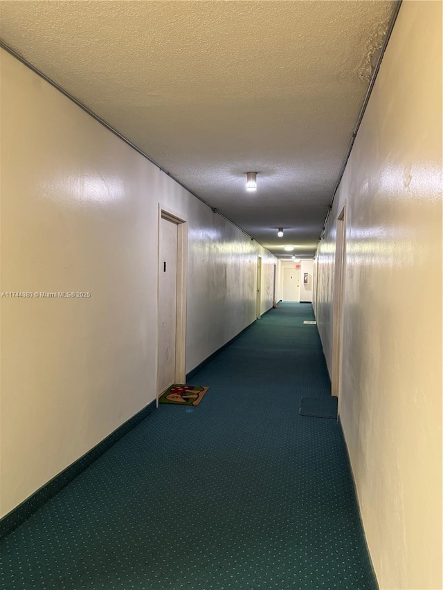 hall featuring carpet floors and a textured ceiling