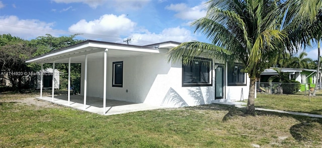 view of home's exterior with a patio, stucco siding, a lawn, fence, and an attached carport