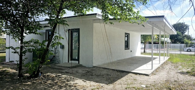 view of home's exterior featuring fence, a carport, and stucco siding