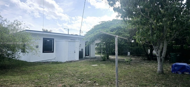 rear view of property featuring a lawn and stucco siding