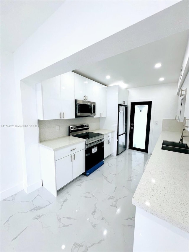 kitchen featuring marble finish floor, appliances with stainless steel finishes, a sink, and white cabinets