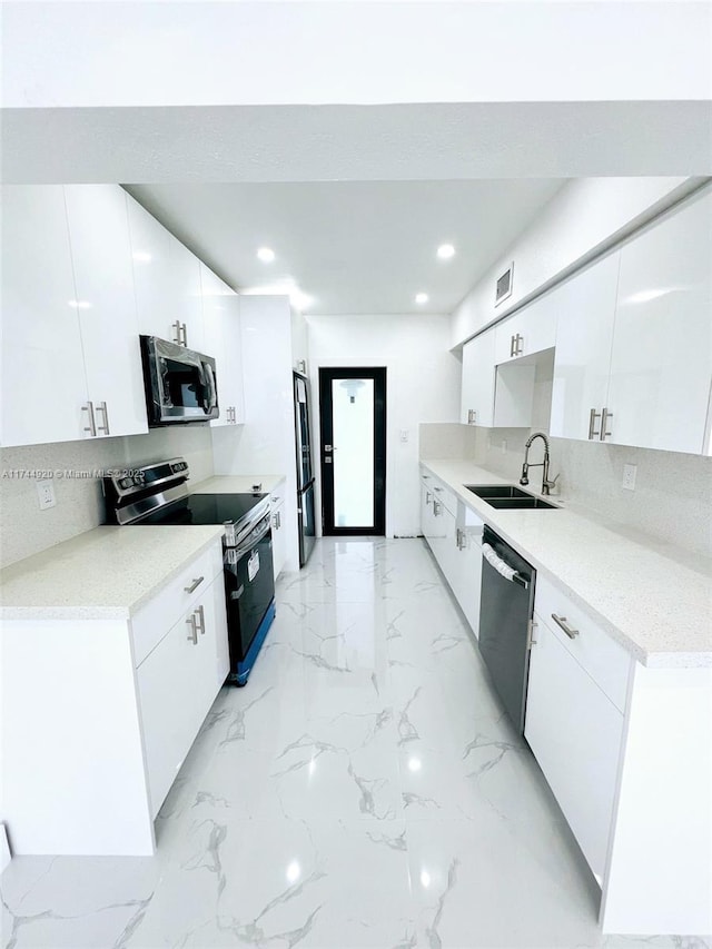 kitchen with stainless steel appliances, light countertops, a sink, and white cabinetry