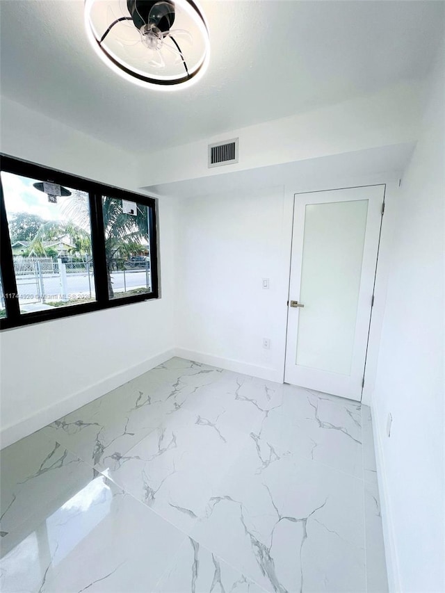 unfurnished room featuring marble finish floor, visible vents, and baseboards