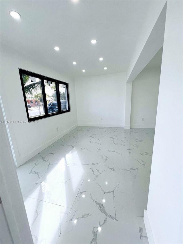 empty room with recessed lighting, marble finish floor, and baseboards