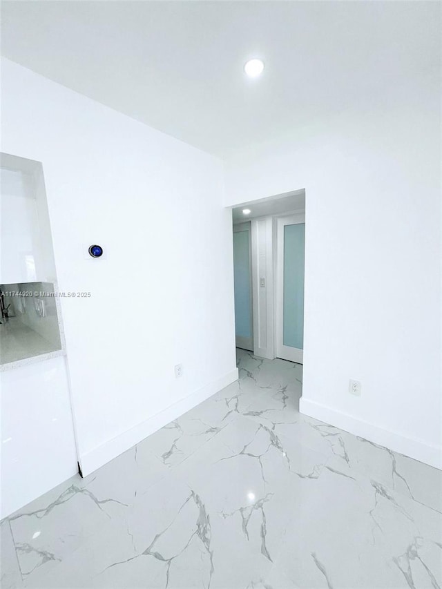 empty room featuring marble finish floor, recessed lighting, and baseboards