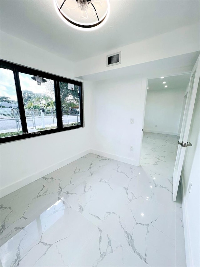 spare room featuring marble finish floor, visible vents, and baseboards