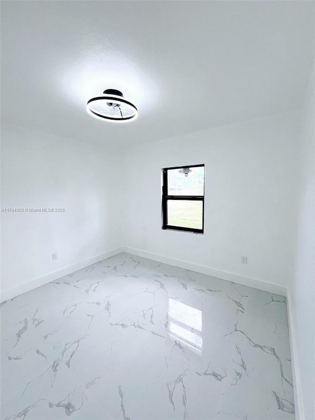 spare room with marble finish floor and baseboards