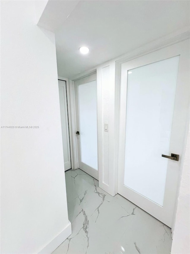 hallway with marble finish floor and baseboards